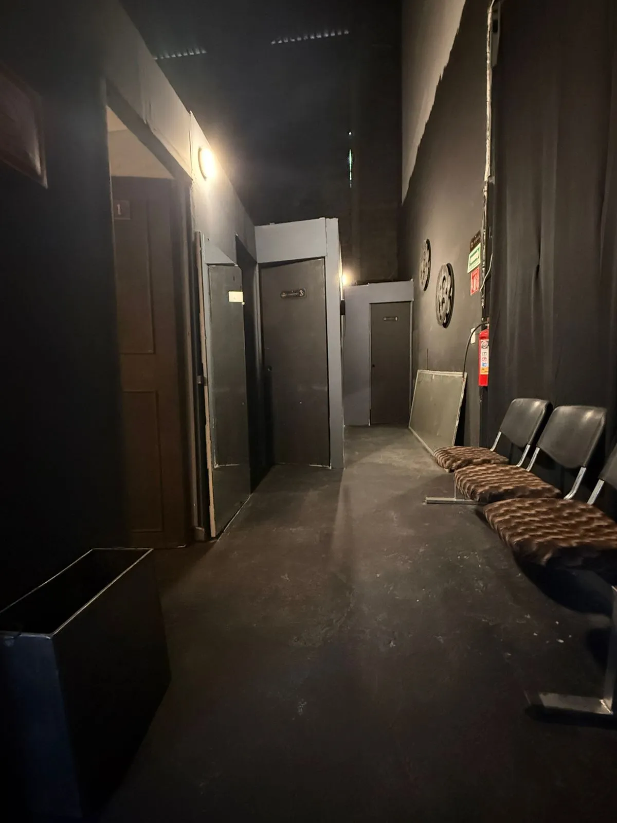 Pasillo de camerinos tras bambalinas en el Teatro Balderas, con puertas numeradas.