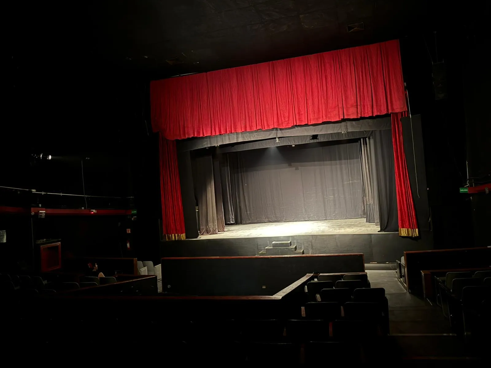 Escenario del Teatro Balderas con el telón rojo abierto y bambalinas grises al fondo.