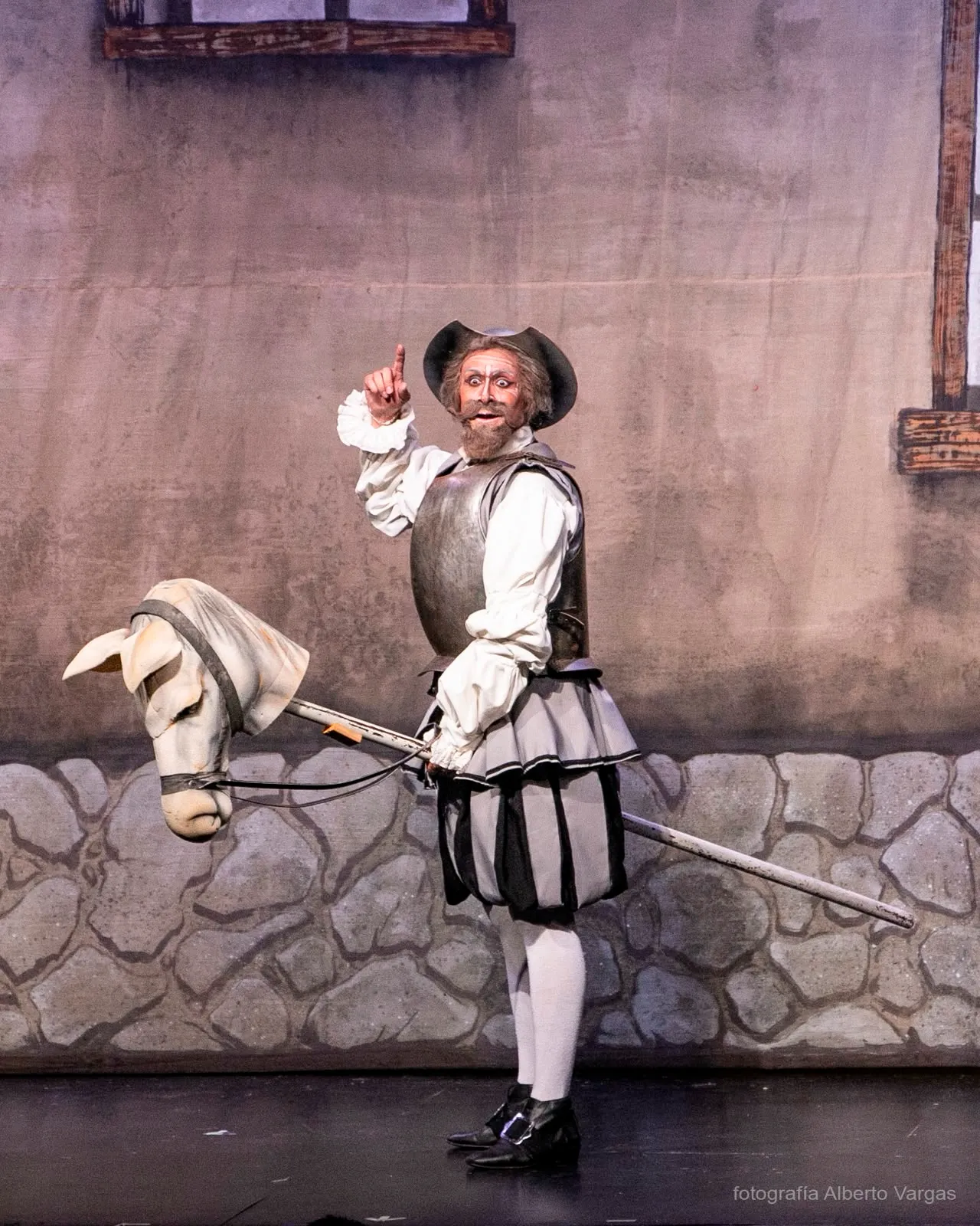 Don Quijote con armadura y su caballo de palo en una escena de la obra.