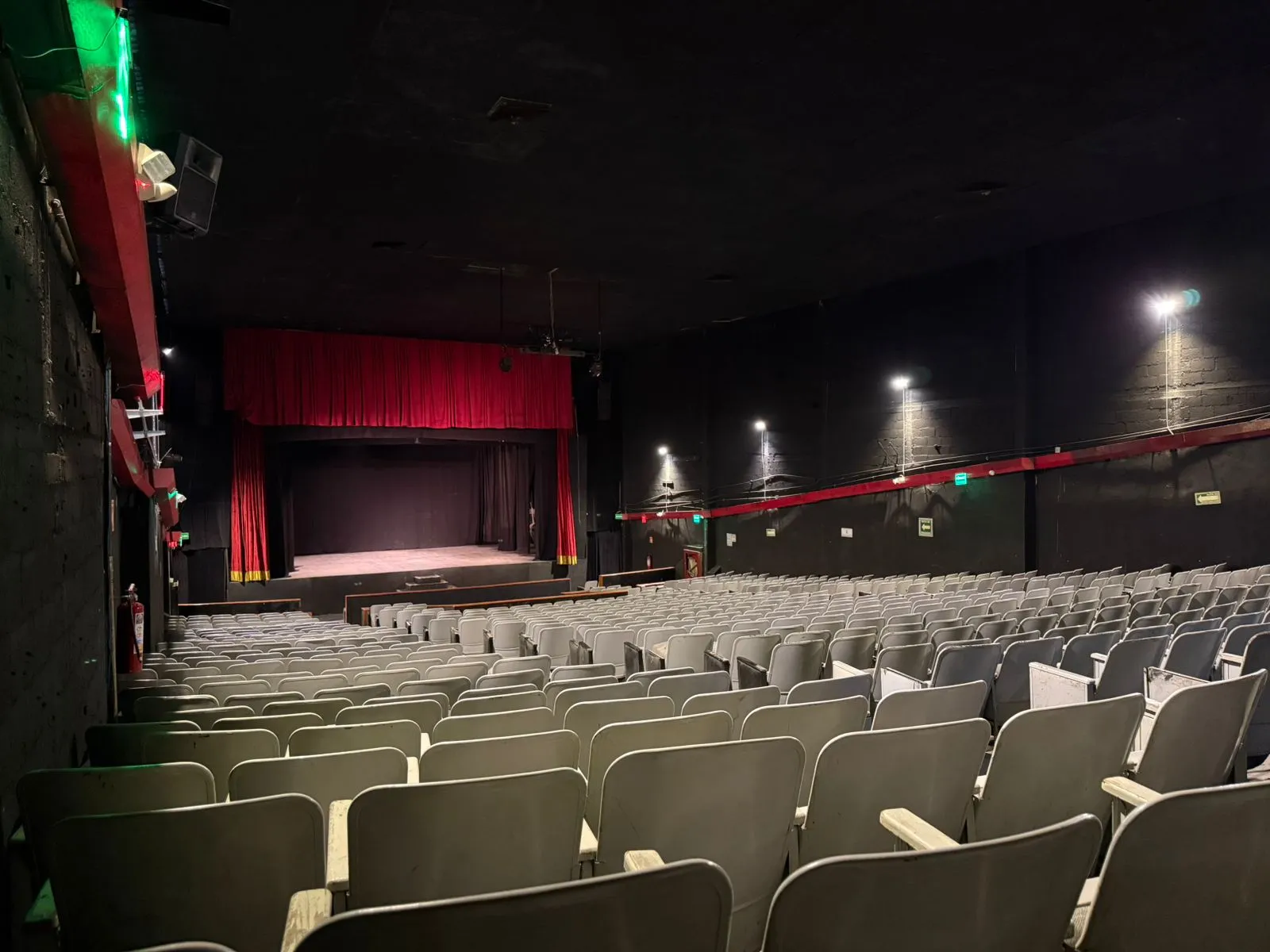 Sala del Teatro Balderas en perspectiva diagonal, con el escenario y el telón rojo al fondo.
