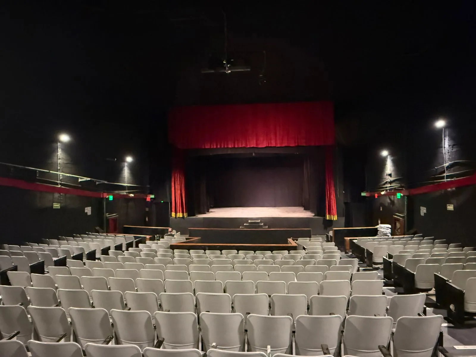 Butacas del Teatro Balderas orientadas hacia el escenario y su gran telón rojo con guardamalleta.