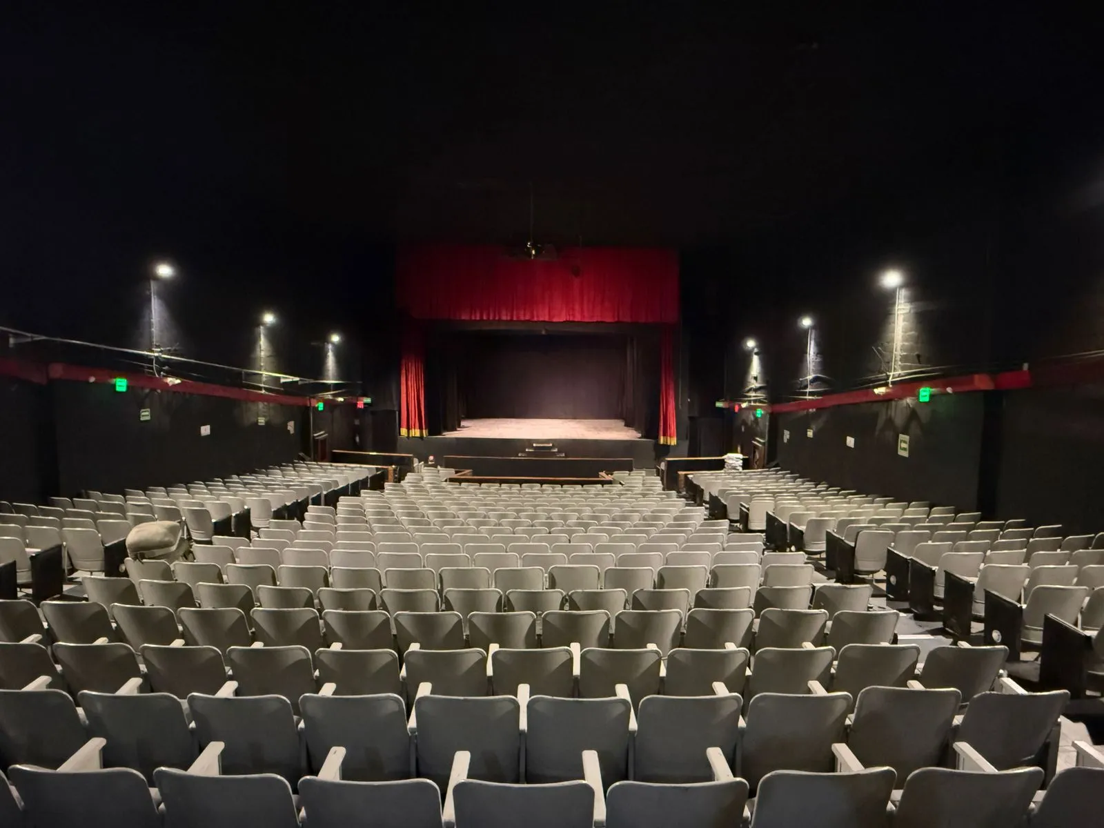 Vista panorámica de la sala del Teatro Balderas: butacas frente al escenario con el telón rojo cerrado.