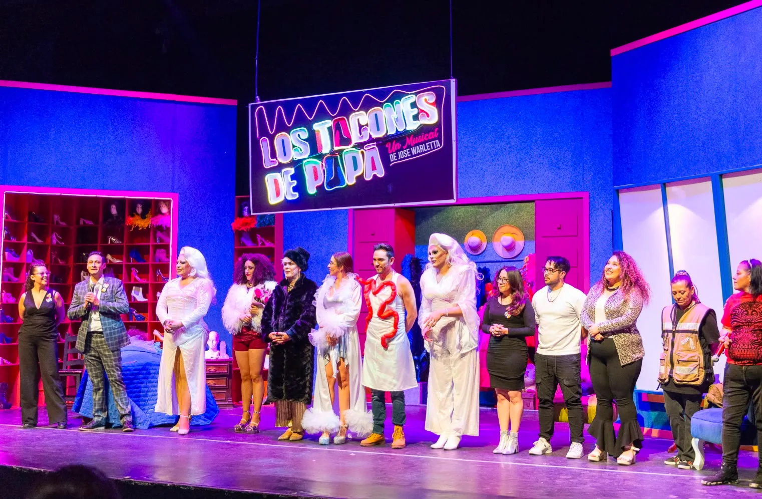 Elenco de Los Tacones de Papá saludando al público al final de la función, bajo la marquesina de neón del musical.